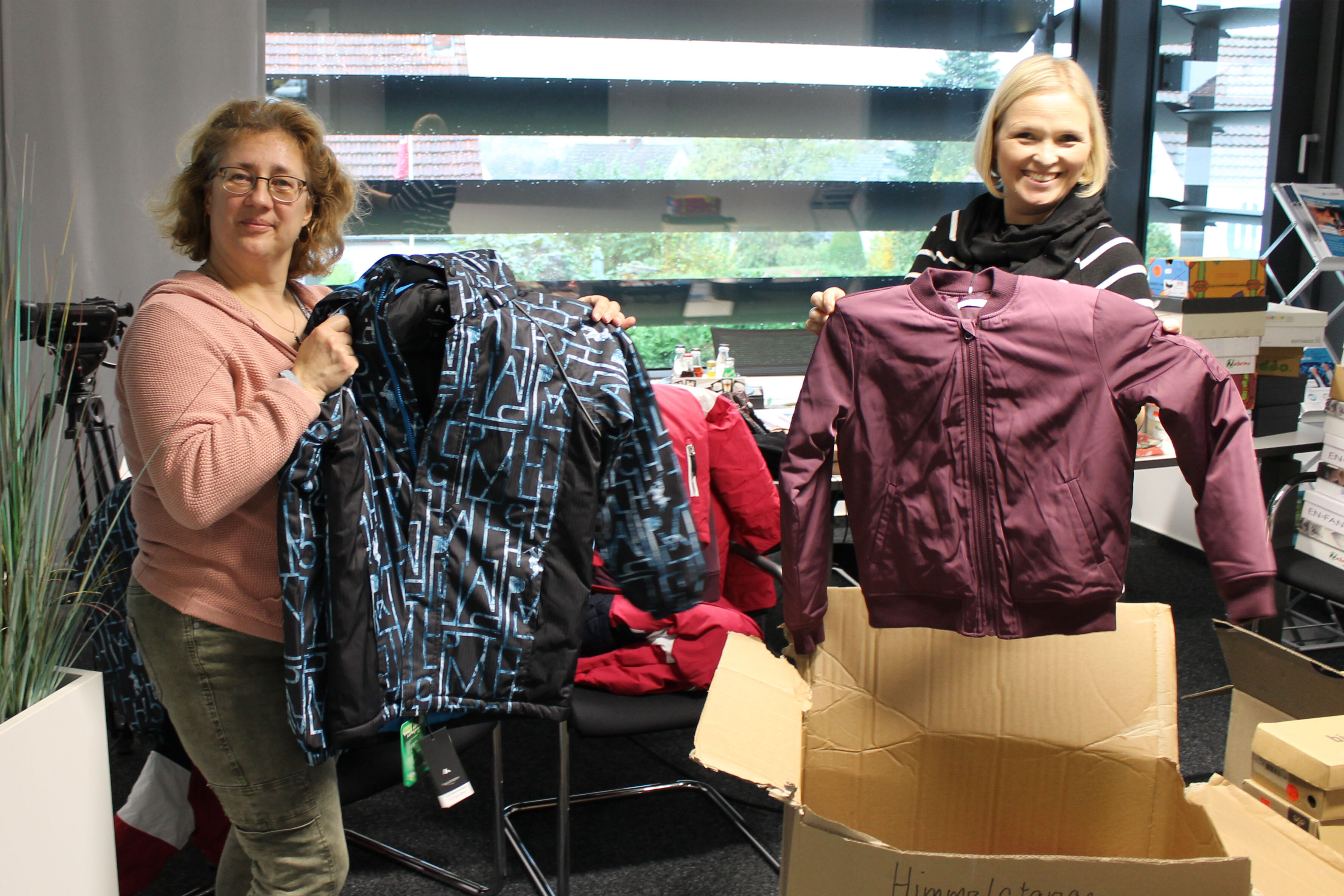 Zwei Mitarbeiterinnen von GTK Scotti kinderglück freuen sich über Kleiderspenden