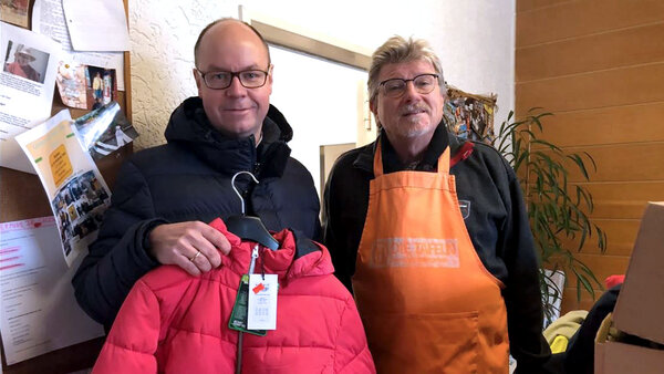 Kai Kröger, Vorsitzender von GTK Scotti Kinderglück, und ein Tafel-Mitarbeiter mit gespendeten Kinderjacken