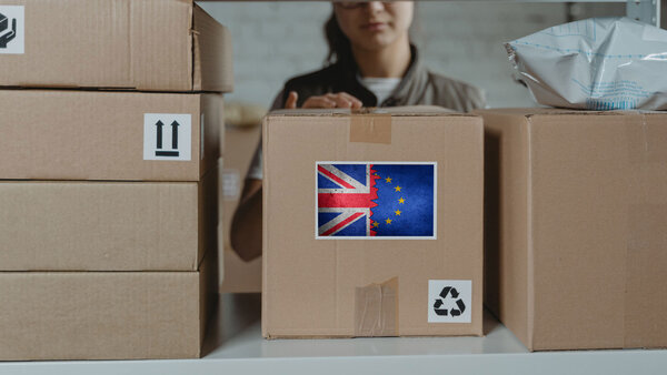 Zu verschickende Pakete im Versandhandel: Ein Paket trägt symbolisch für den Brexit eine halb britische halb europäische Flagge.